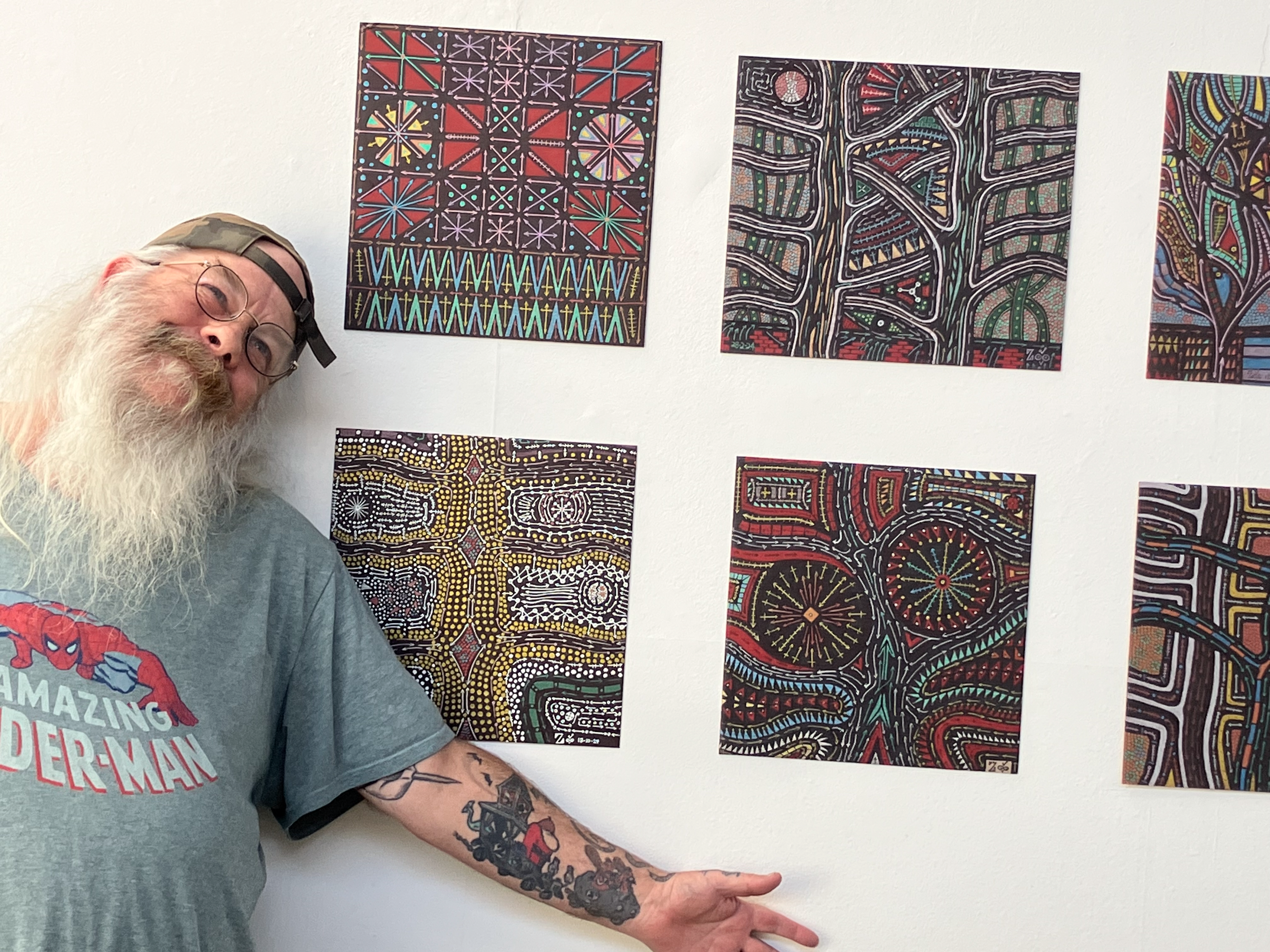 A person with arm stretched out in front of their artwork proudly.