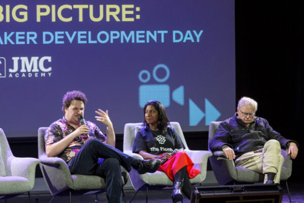 three people sitting in chairs on a stage