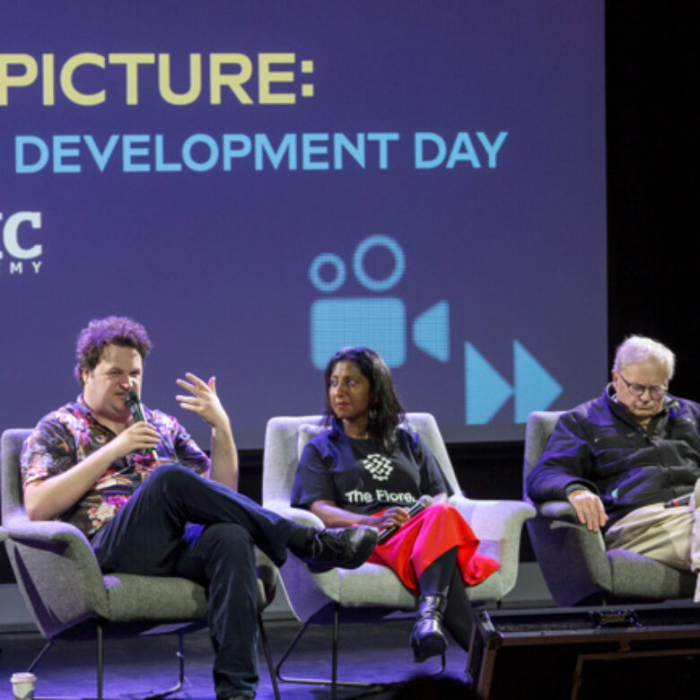 three people sitting in chairs on a stage