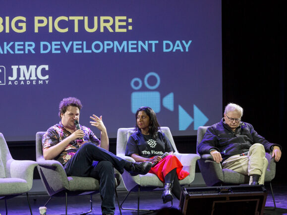 three people sitting in chairs on a stage