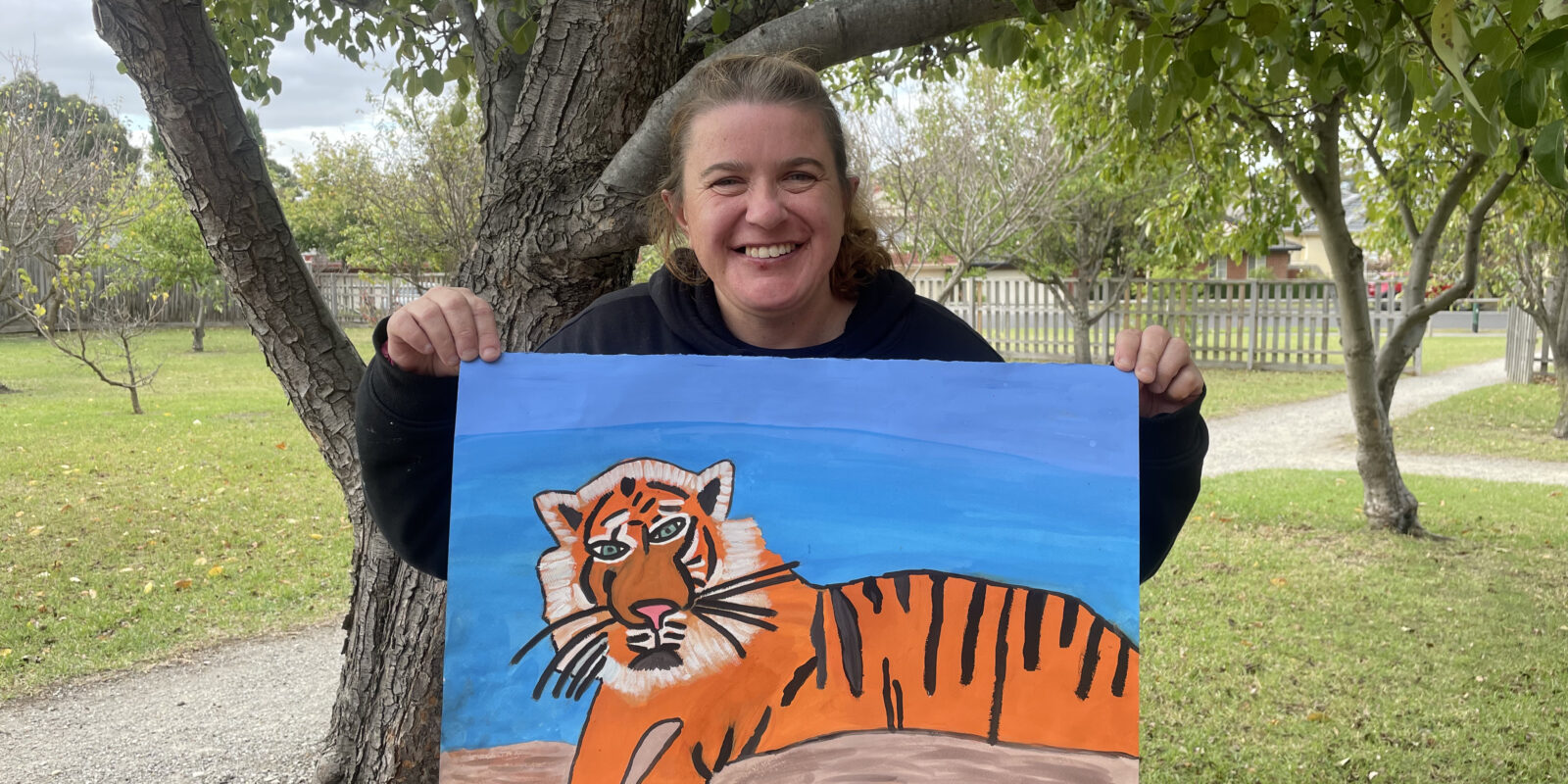Fiona holding up her Sunda Island Tiger painting in the studio garden