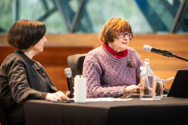 Two people seated at a table with microphones presenting a workshop.