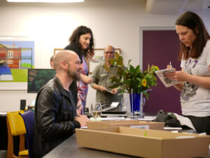 a man is helping someone at reception during an exhibition opening.