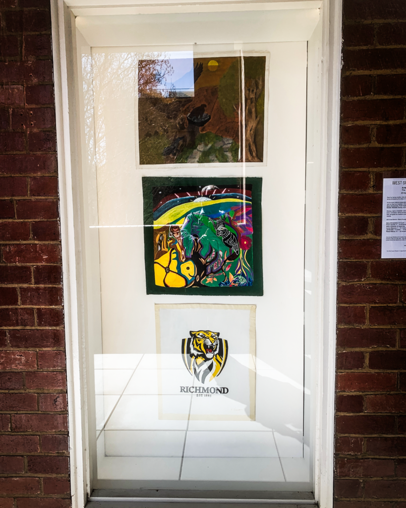 A window cabinet in a brick wall with art work on display.