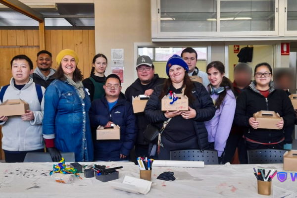 A group photo of people holding their art pieces in studio.