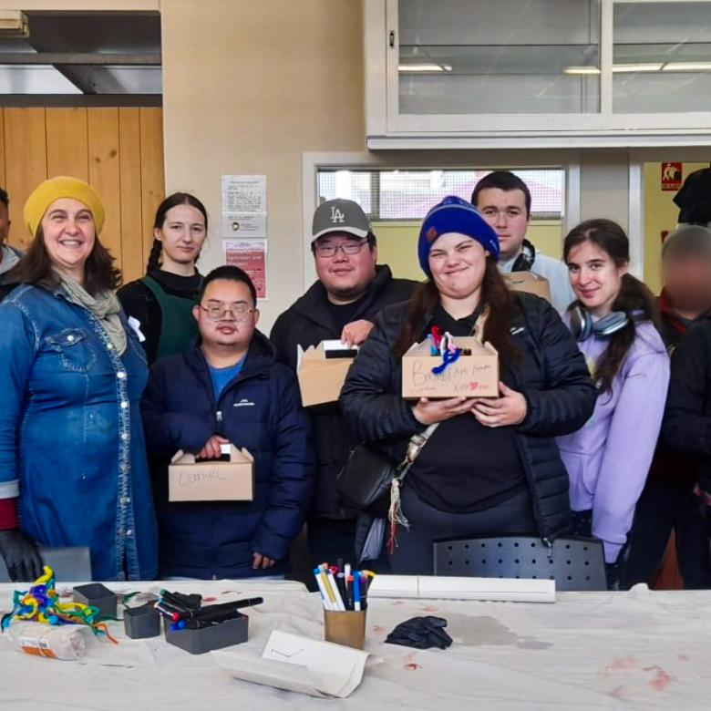 A group photo of people holding their art pieces in studio.