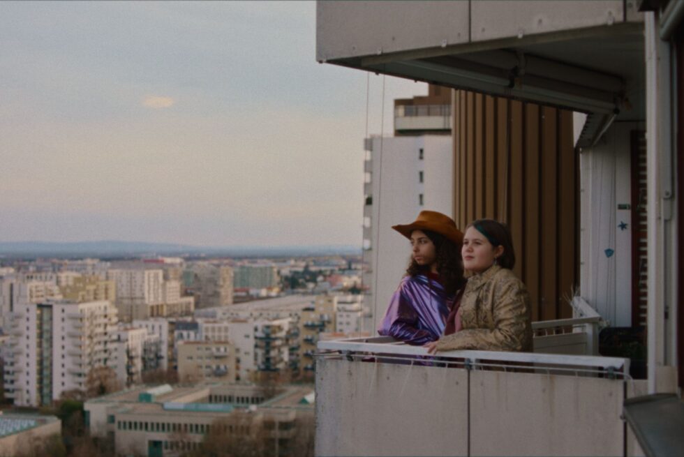 Two people stood on a balcony gazing out at the skyline.