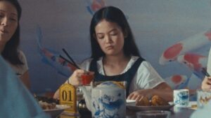 A young person eating at a restaurant with chopsticks.