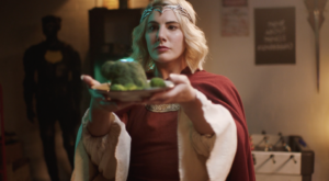 A person in a medieval costume holding out a plate of jelly.