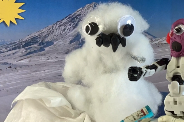 A snowman is in front of snowy mountains with his friend.