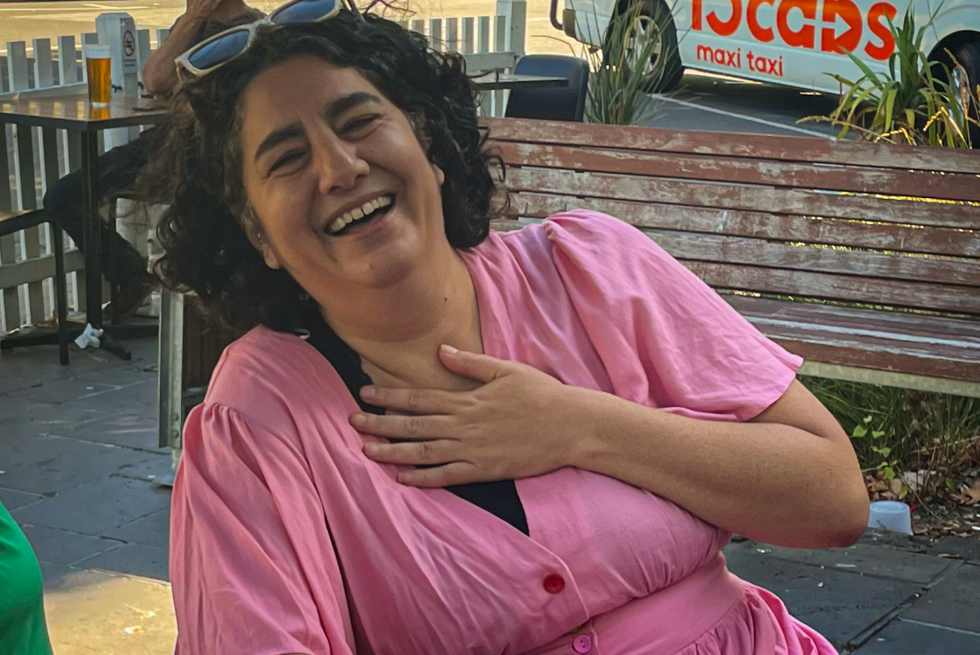 Nikki laughing with their hand on their chest