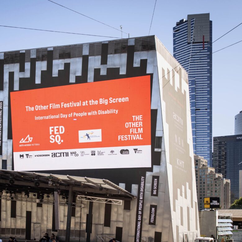 Outdoor screen at Fed Square showing an orange slide that reads ‘The Other Film Festival at the Big Screen’
