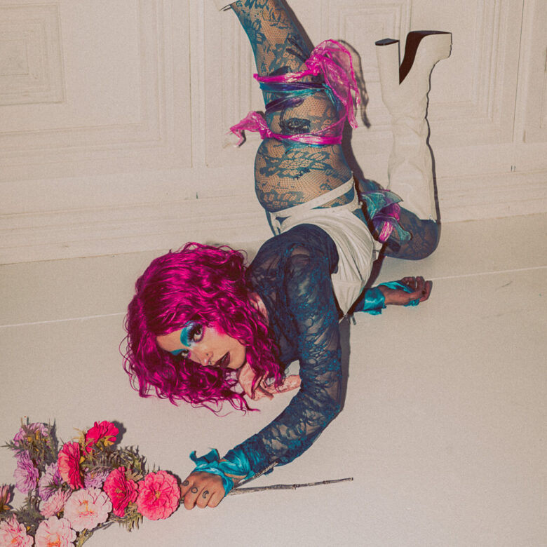 A performer doing a handstand against a wall looking at the camera.