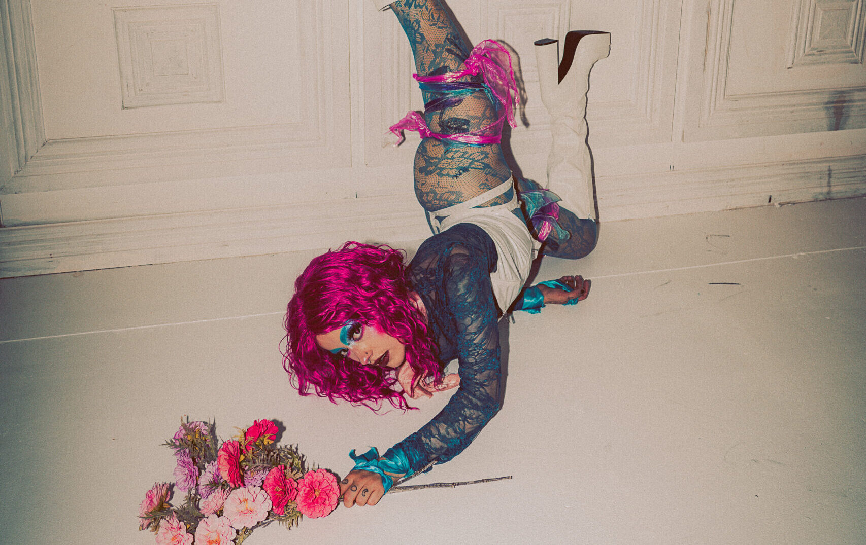 A performer doing a handstand against a wall looking at the camera.